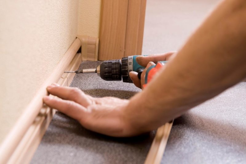 Fixing a skirting board with a screwdriver.